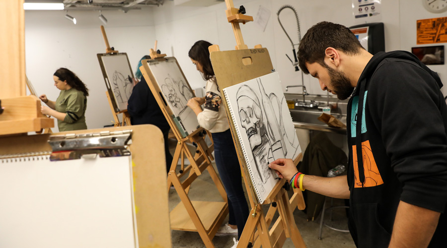 A Suffolk student sketches on an easel in an art studio.