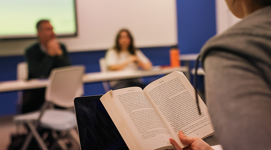 Student reading aloud from a book during a FYW class