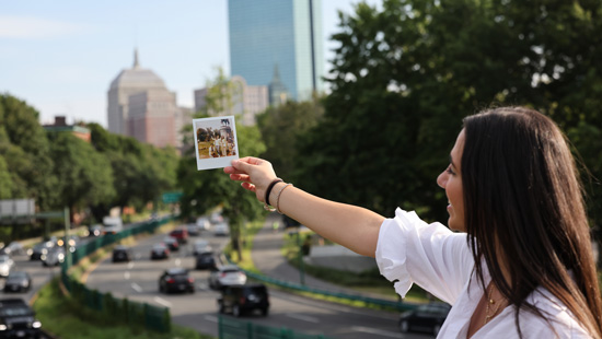 Suffolk student Angela shows off a polaroid picture overlooking the Boston skyline.