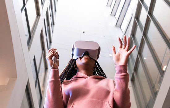 A Suffolk student uses a VR headset in the atrium of Miller Hall.