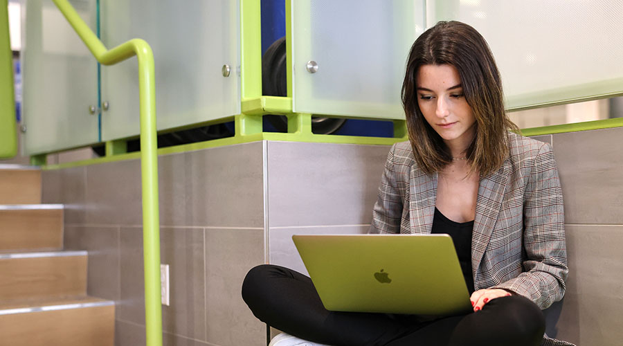 Student sitting in the Samia Academic Center working on her laptop