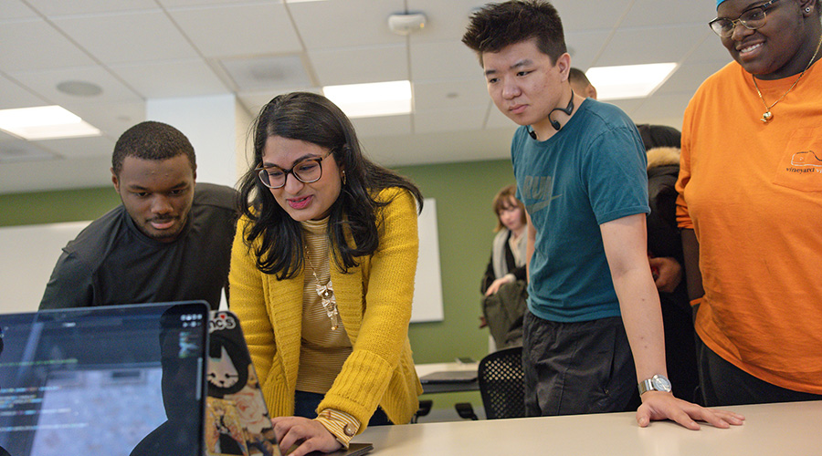 Suffolk students leaning over a computer screen