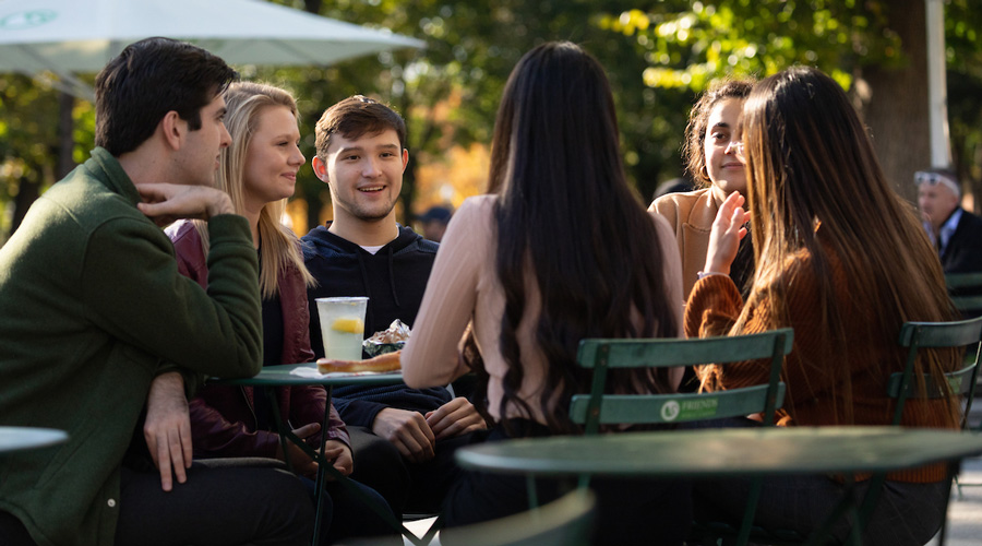 A group of Suffolk students eating lunch together at a table in Boston Common.