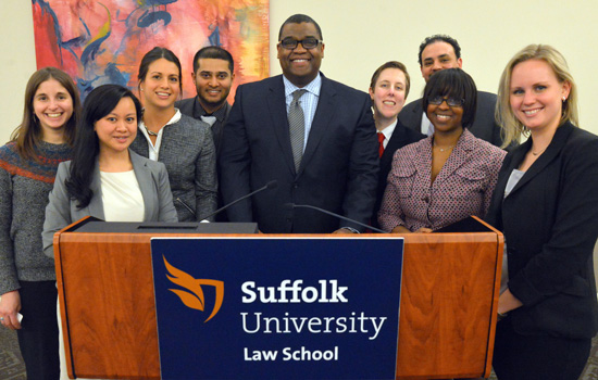 Suffolk University Law Students gather around the podium after an event.
