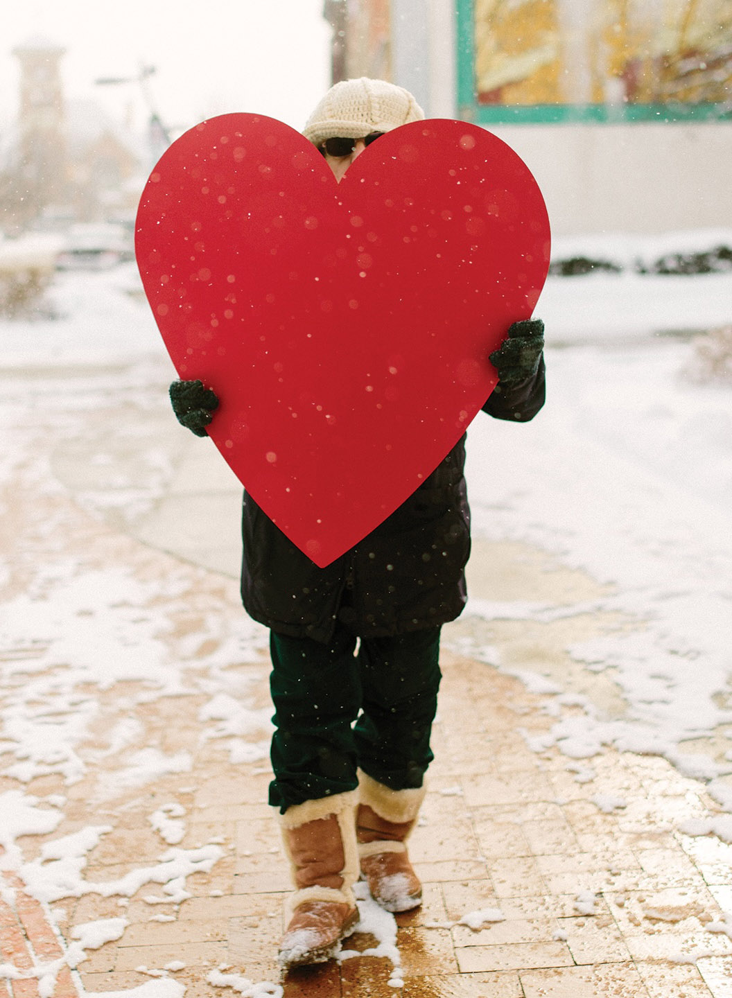 Stock photo of a person holding a large red cutout of a heart in front of their face.