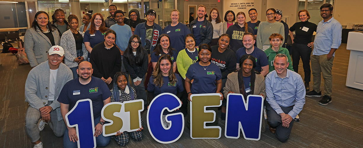 First-Gen Students and staff pose together for a photo with a banner at an event