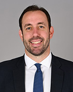 Portrait of Trustee Joe Delisi, smiling in black suit jacket and blue tie