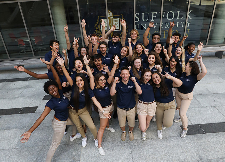 Suffolk students stand in front of a city building and welcome new students.