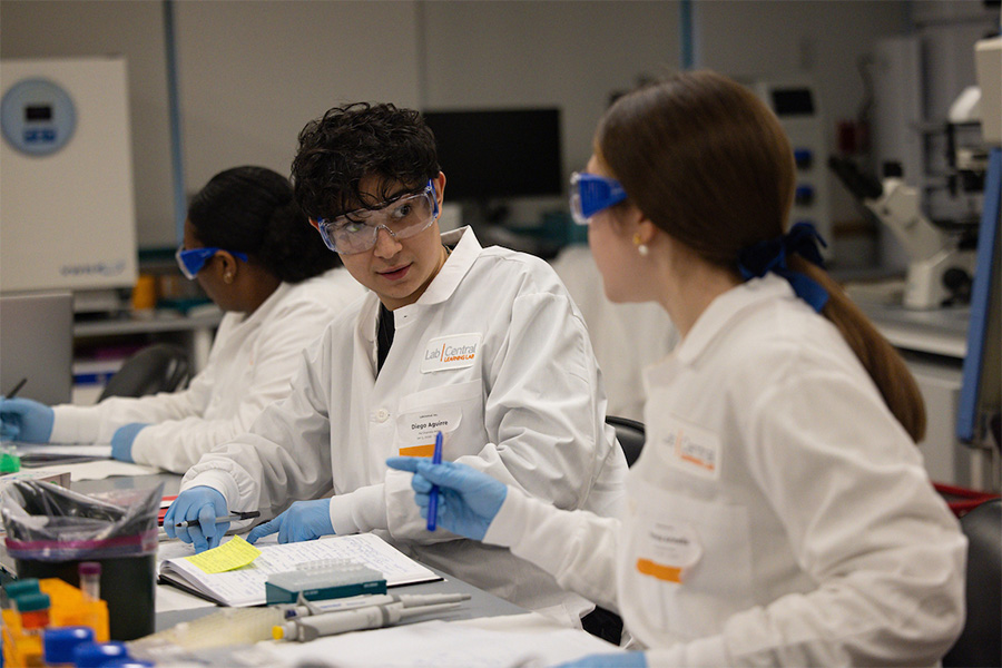 Suffolk students in lab safety gear working together in a class.