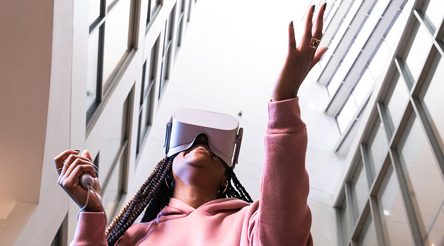 A Suffolk student wearing a VR headset and reaching out in a dynamic space.