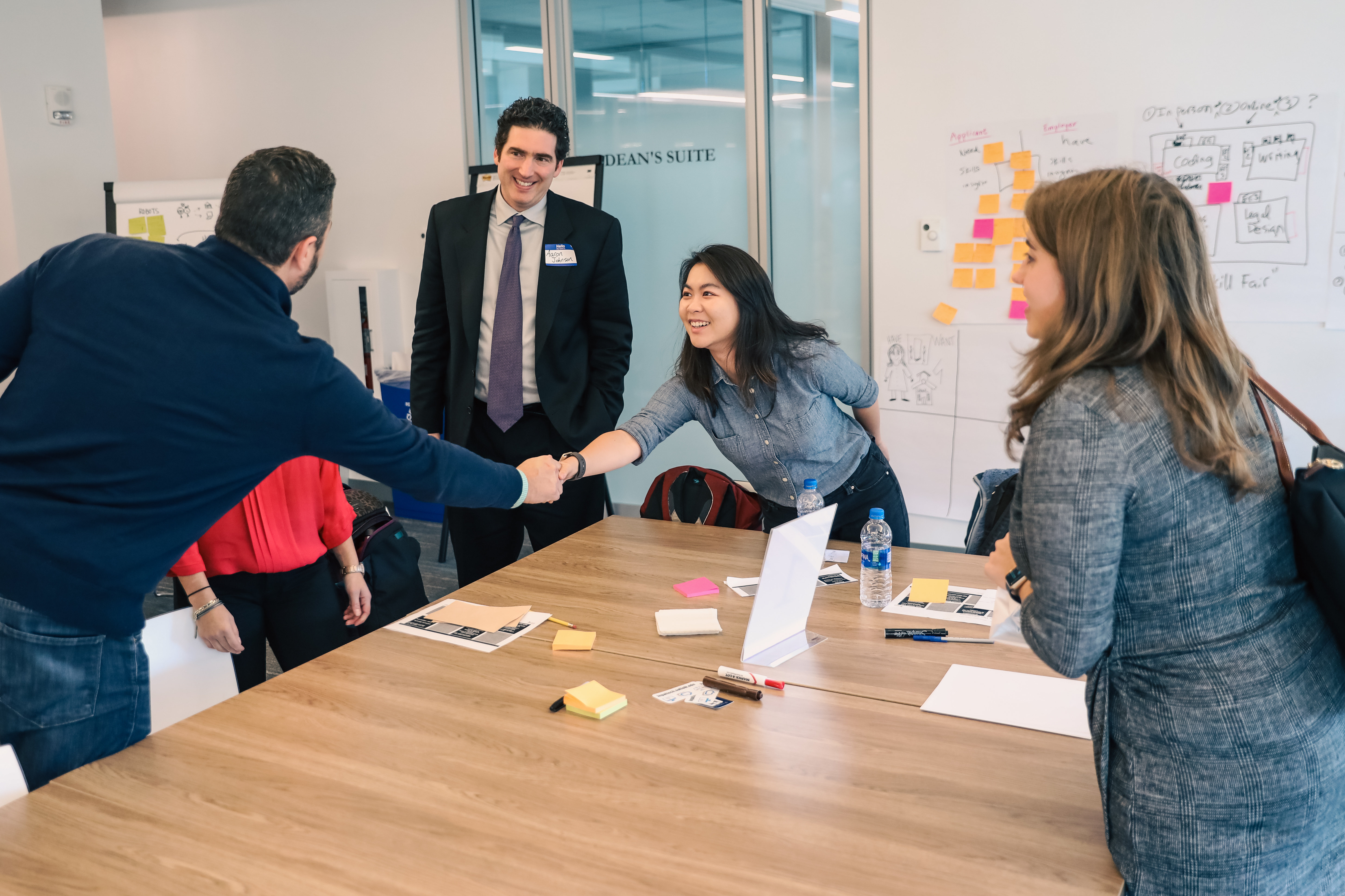 Two people shake hands in a Suffolk Conference room.