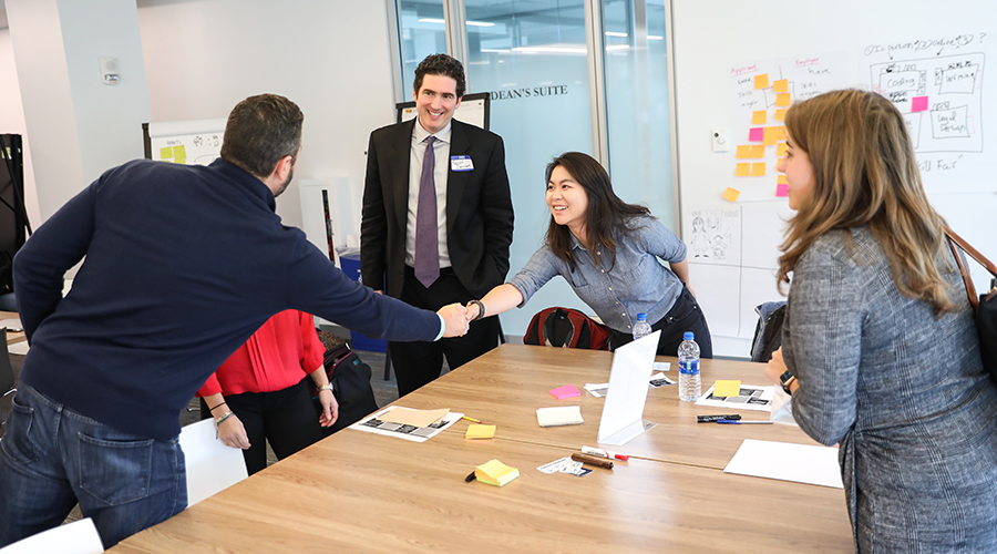 Two people shake hands in a Suffolk Conference room.