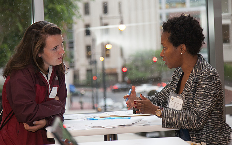 Two woman with nametags sit together in discussion.
