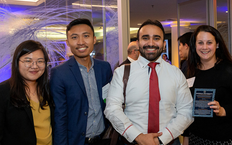 Four event attendees stand and pose together for a photo.