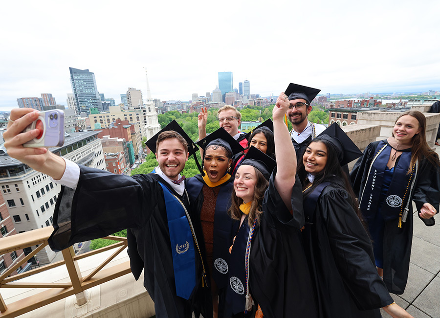 Suffolk students taking a photo together on the 73 Tremont balcony before Commencement.