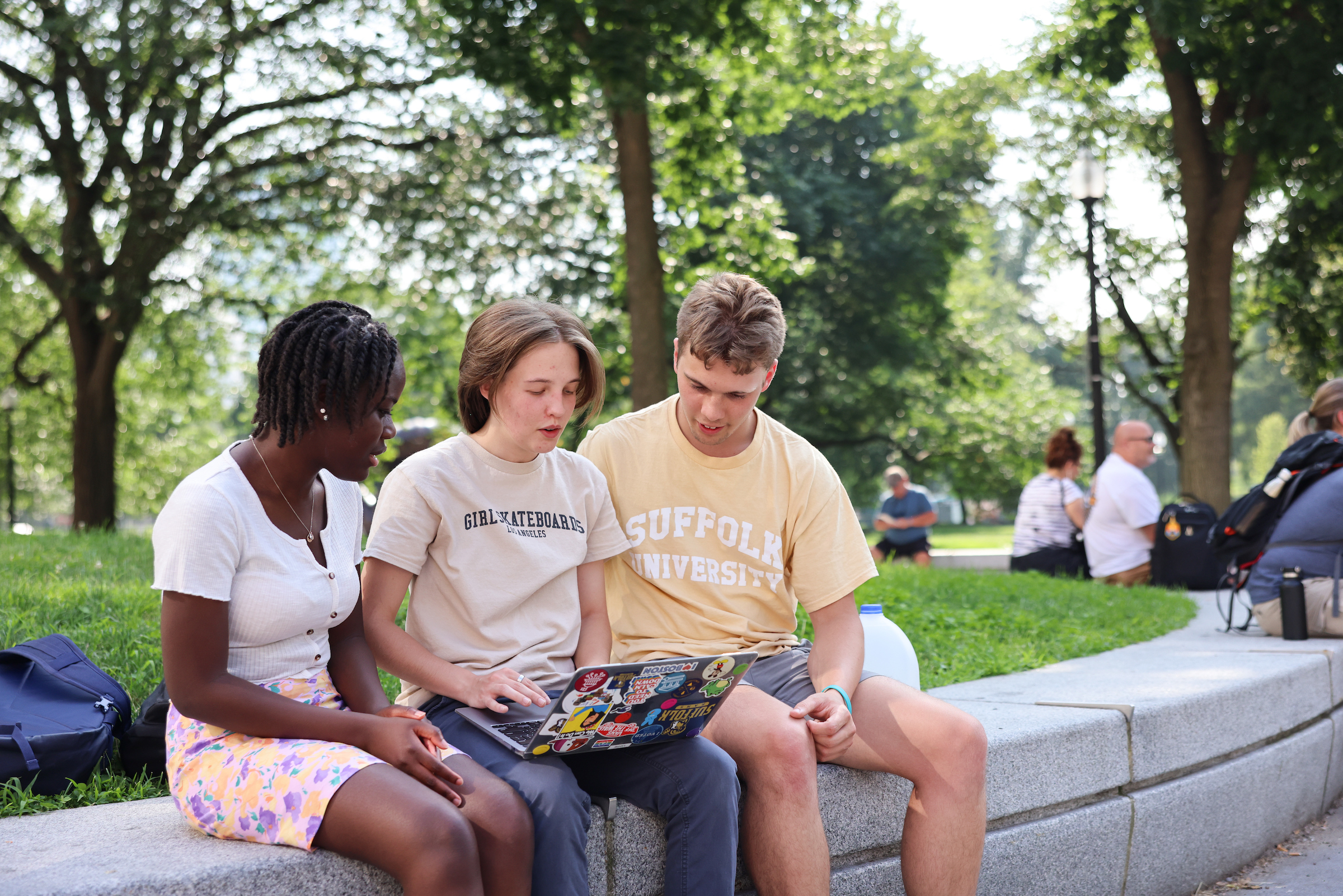 Three Suffolk Students sit together on the Boston Common