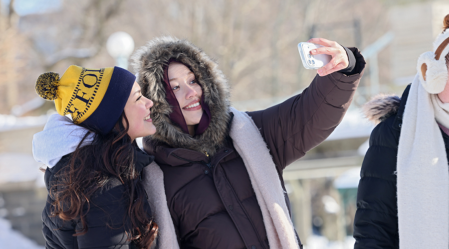 Two Suffolk students pose together for a selfie while walking in Boston on a Snow Day.
