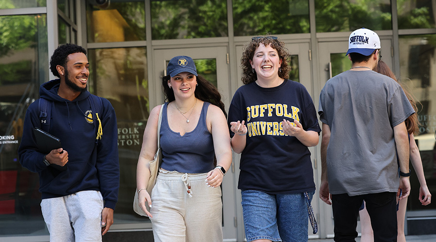 Suffolk students walking confidently out of the Samia Academic Center on campus.