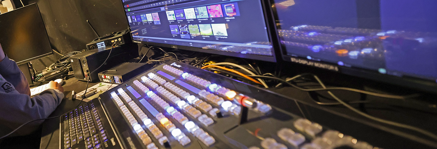 A lit production switchboard and screen in Suffolk University's Studio 73.