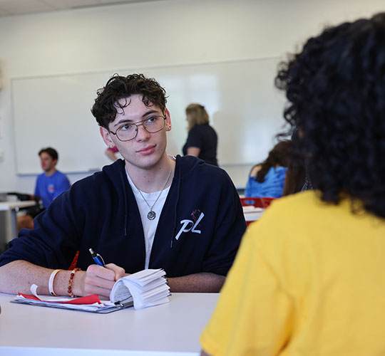 Two students sit at a table talking