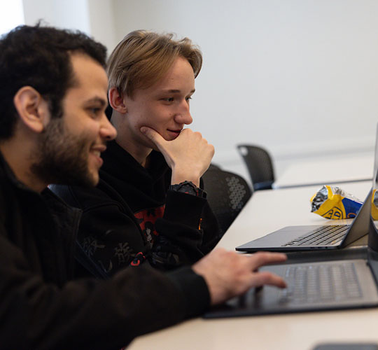 Two students collaborate on a laptop