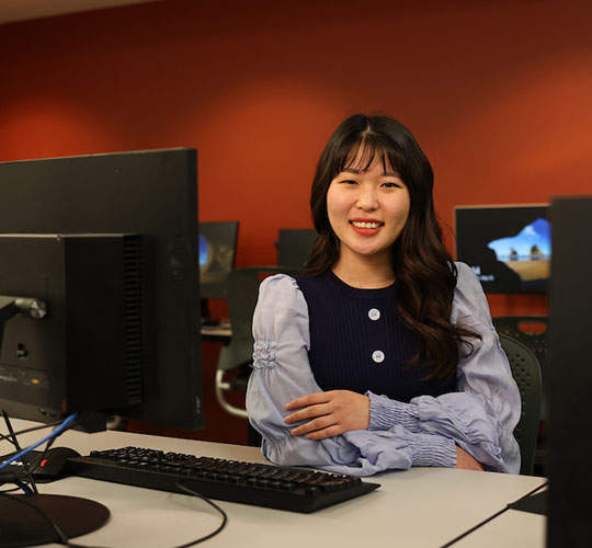 Student sitting in classroom facing the camera and smiling