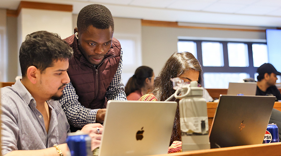 Several students gesturing at a laptop screen