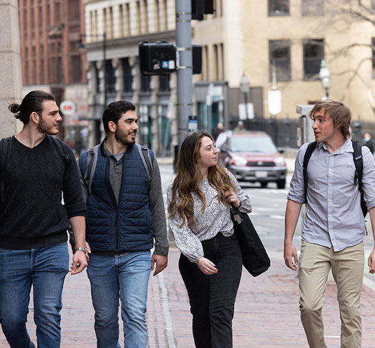 Four students walk down a street in Downtown Boston