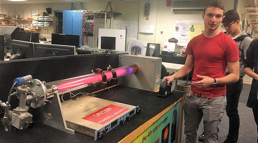 Man demonstrates how a machine that handles plasma fusion works to students.