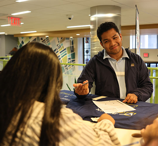 Students sitting across each other at a table and smiling