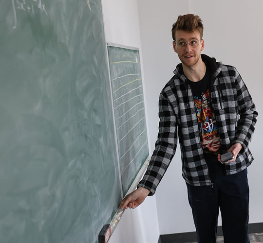Student in a math class writing on a blackboard