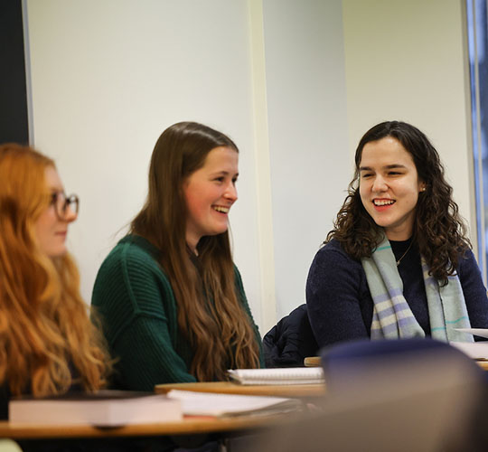 Three students in class smiling