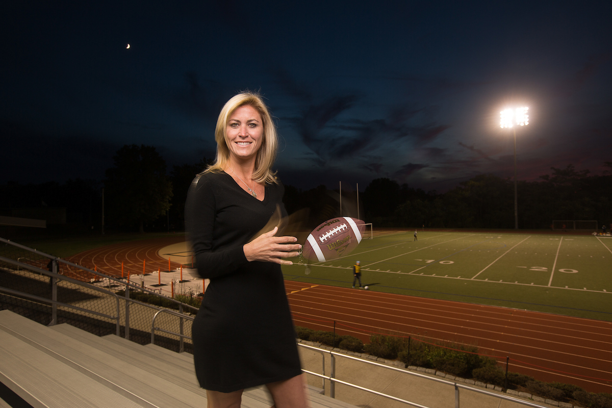 Suffolk alum holding a football at a field. 