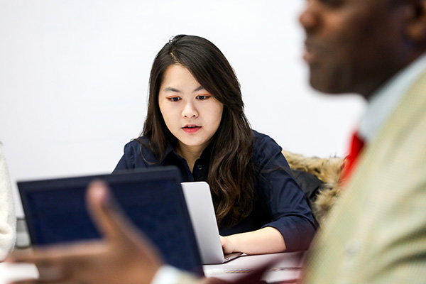 Suffolk University graduate student in classroom with a laptop.