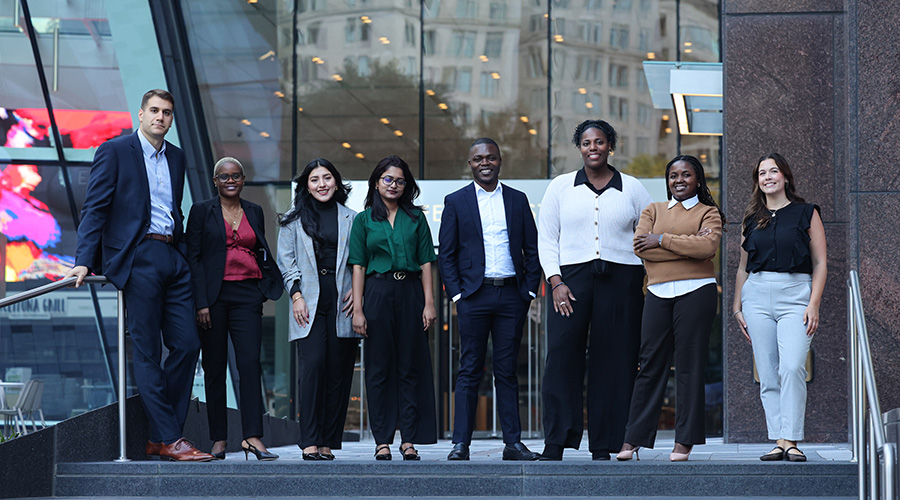 Suffolk University graduate students stand together on steps of a city building.