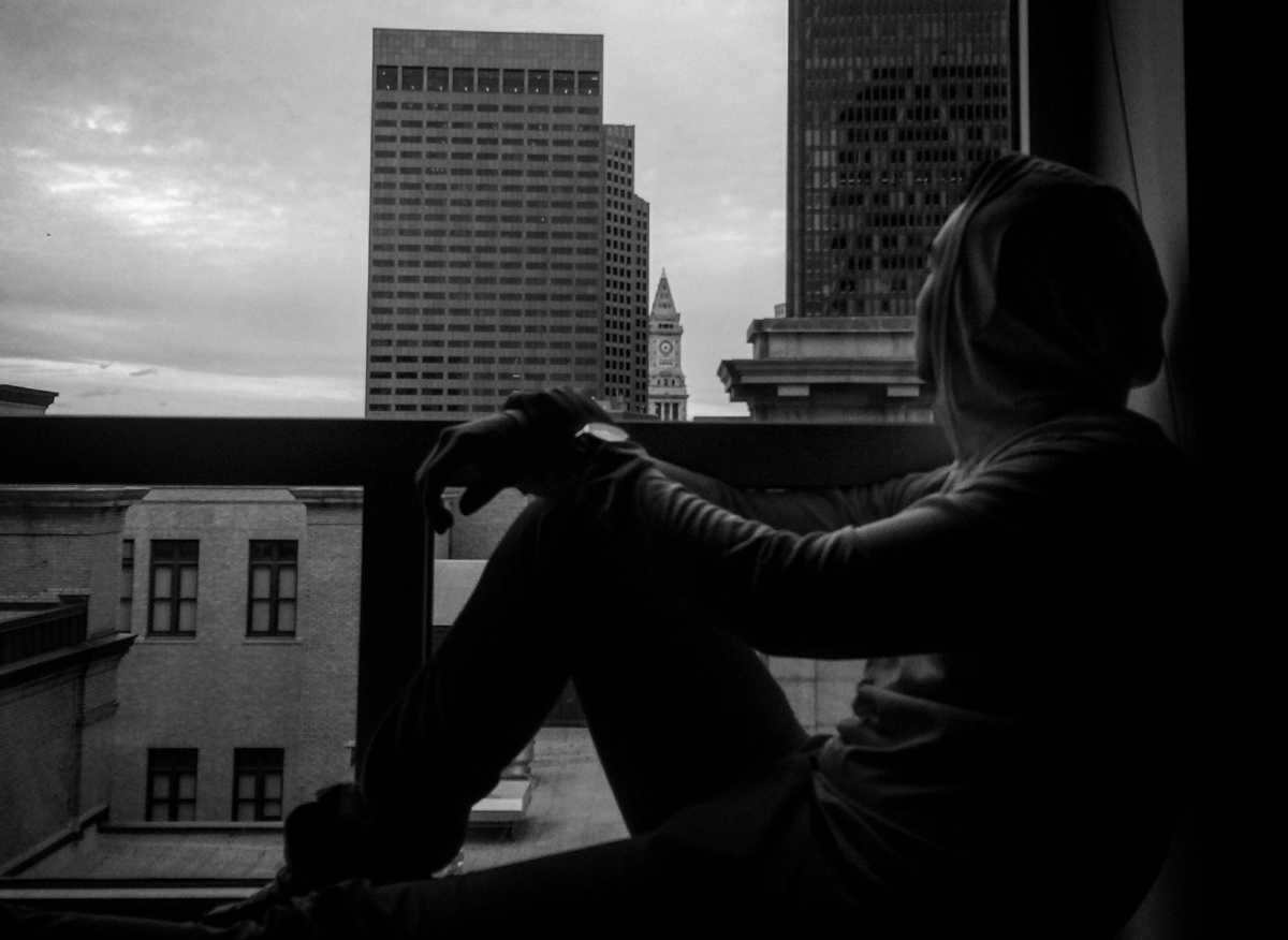 Dan Redznak sitting in his dorm room windowsill looking out over Boston.