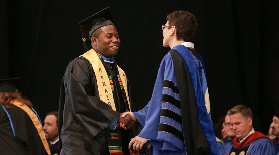 Suffolk student Isaac Boateng shakes hands with Suffolk President Marisa Kelly at his commencement.