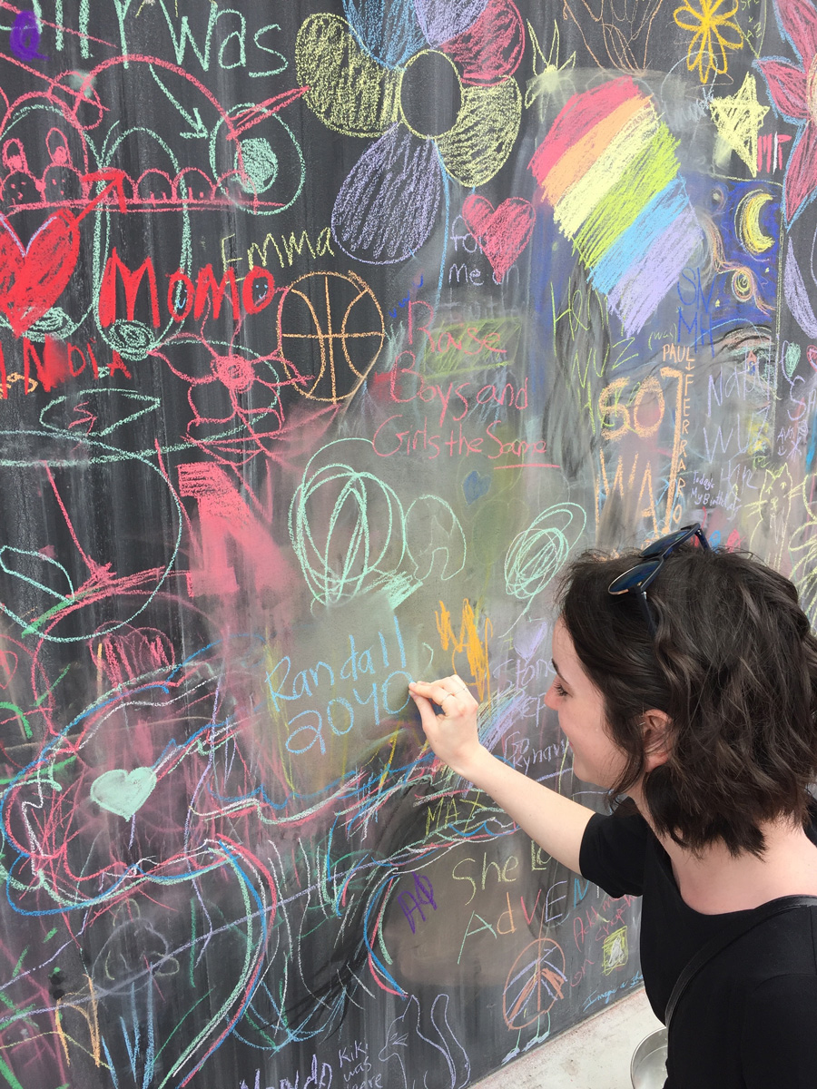 Maggie Randall writing her name on chalk on a graffiti wall.