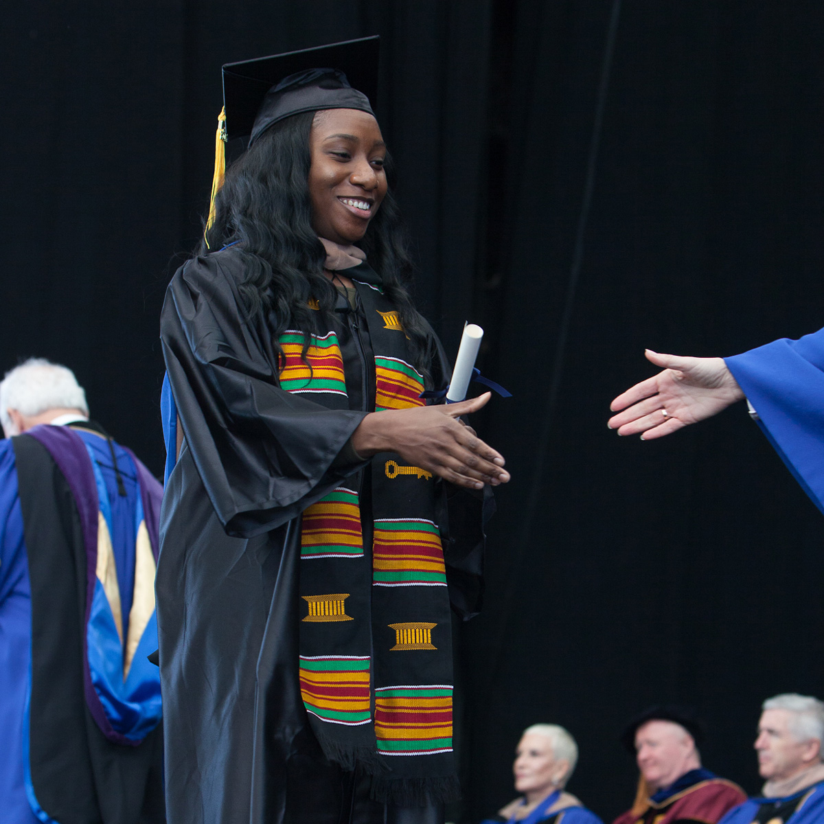 Brittani Cesar preparing to shake an administrator's hand while crossing the stage at Commencement.