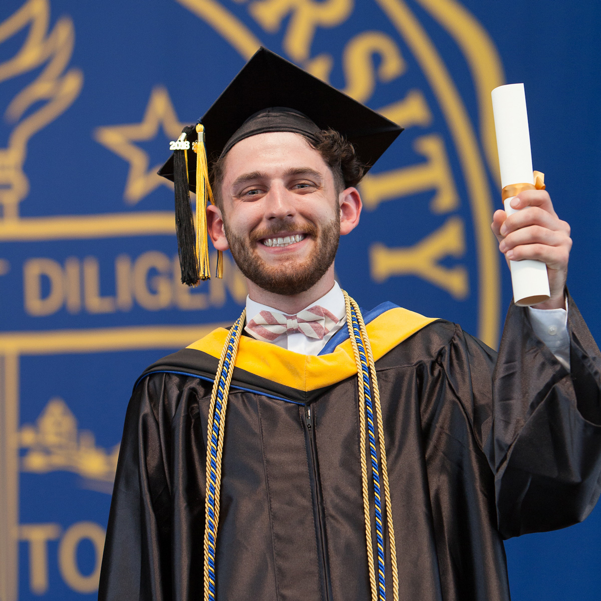 Kevin holding up his scroll on stage during Commencement.