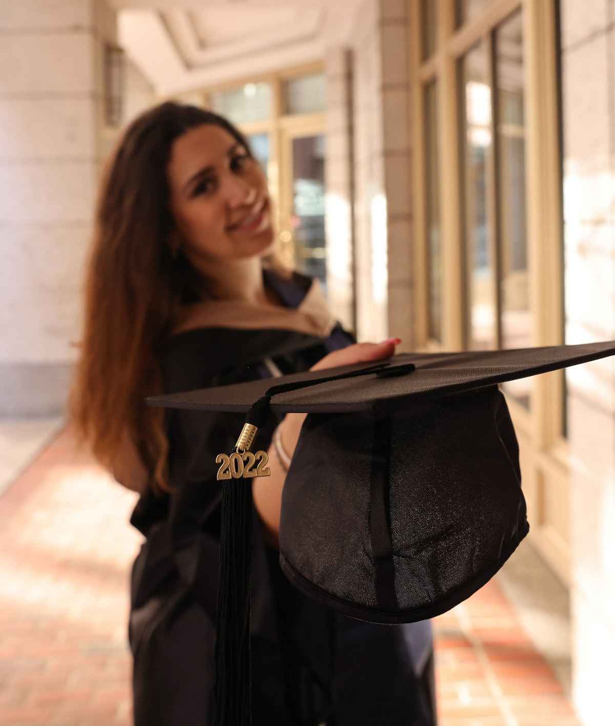 Portrait of Suffolk student Arla holding her graduation cap.