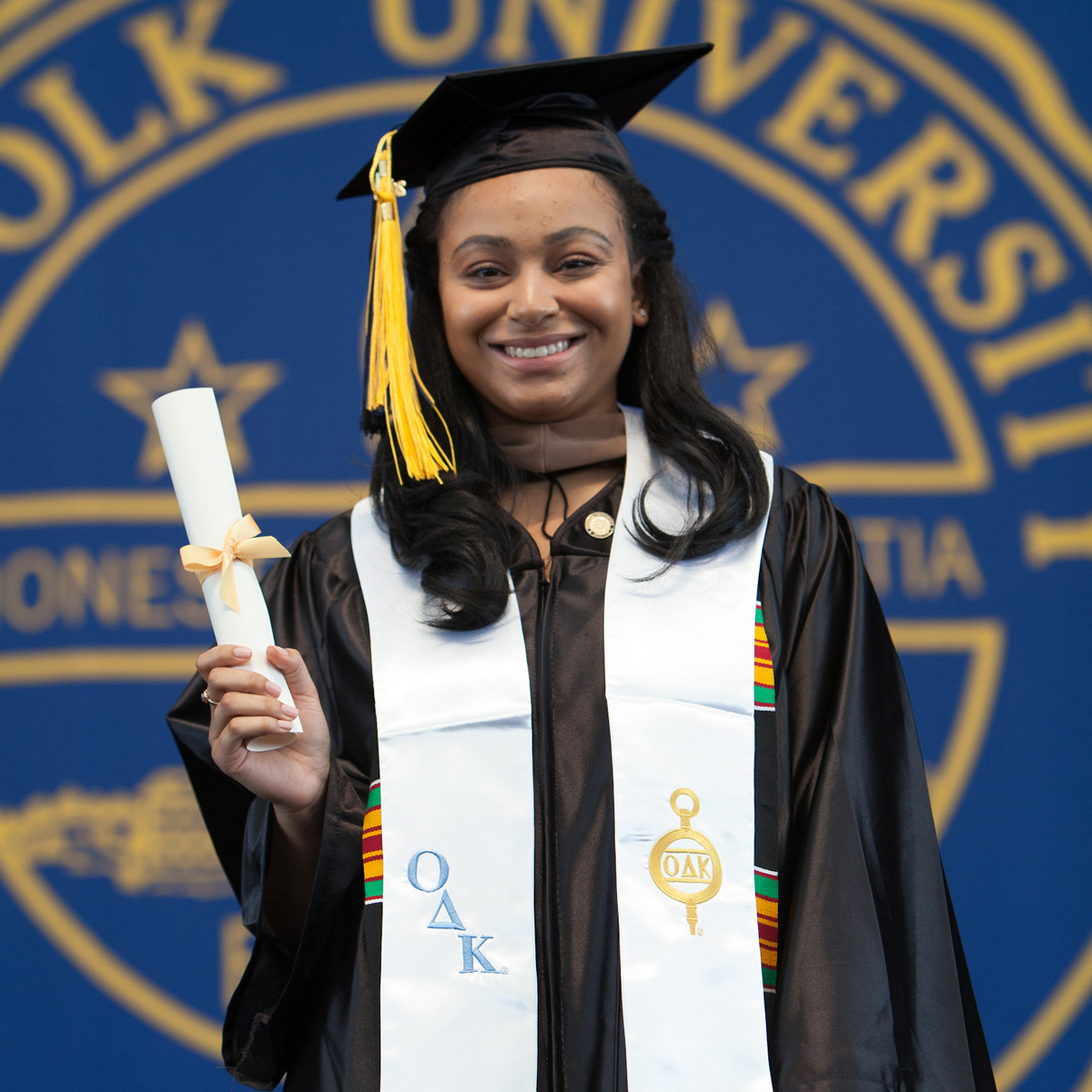 Melissa Guirand holds up her scroll on stage during her Commencement ceremony.