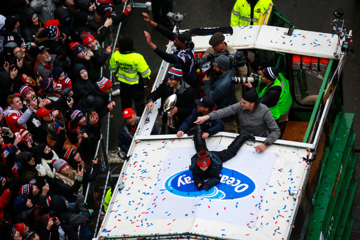 Quarterbacks Tom Brady and Jimmy Garoppolo wave to the crowds from a Duck boat during their victory parade.