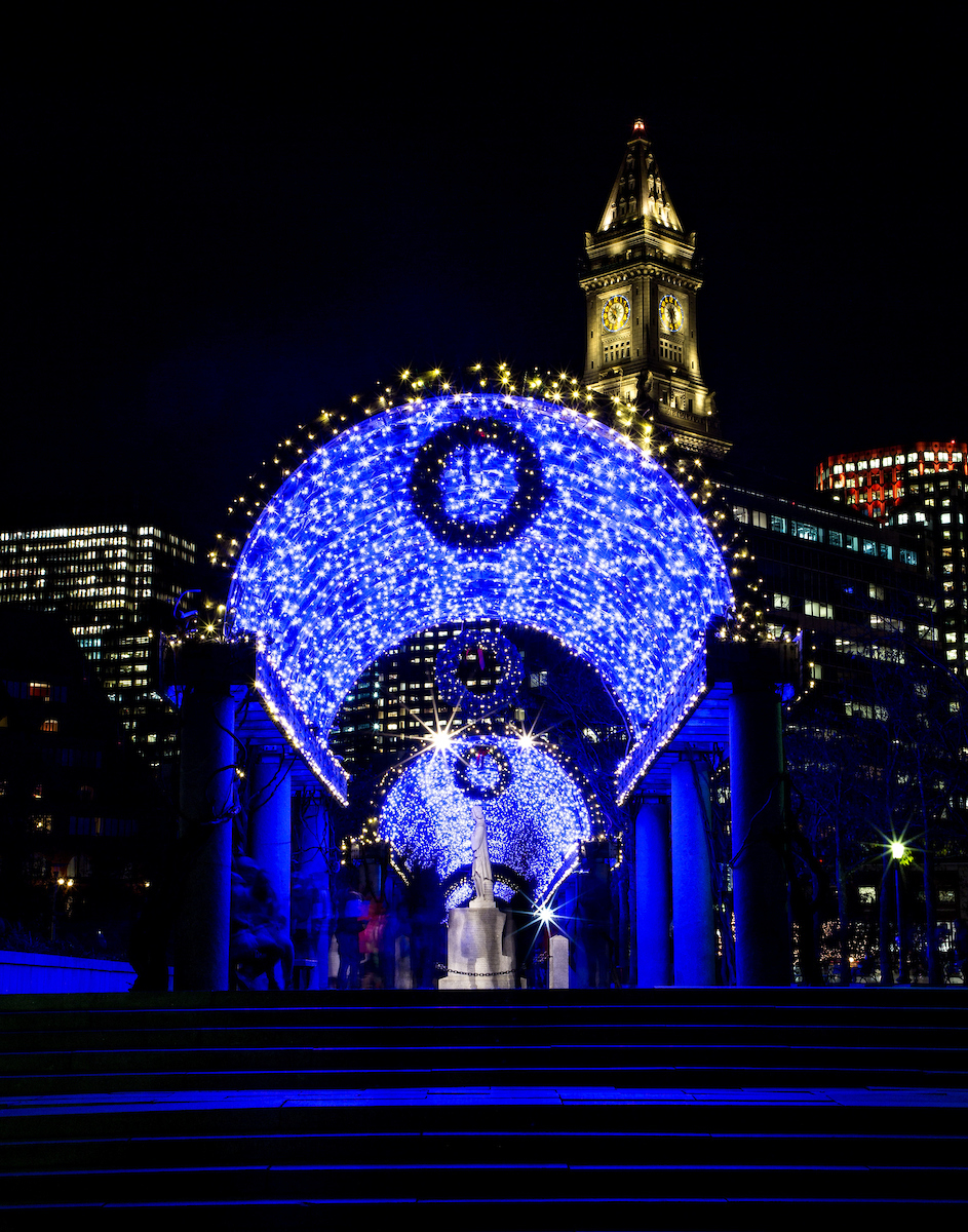 Christopher Columbus Waterfront Park on the Boston Harbor waterfront illuminated from blue lights for the holiday season.