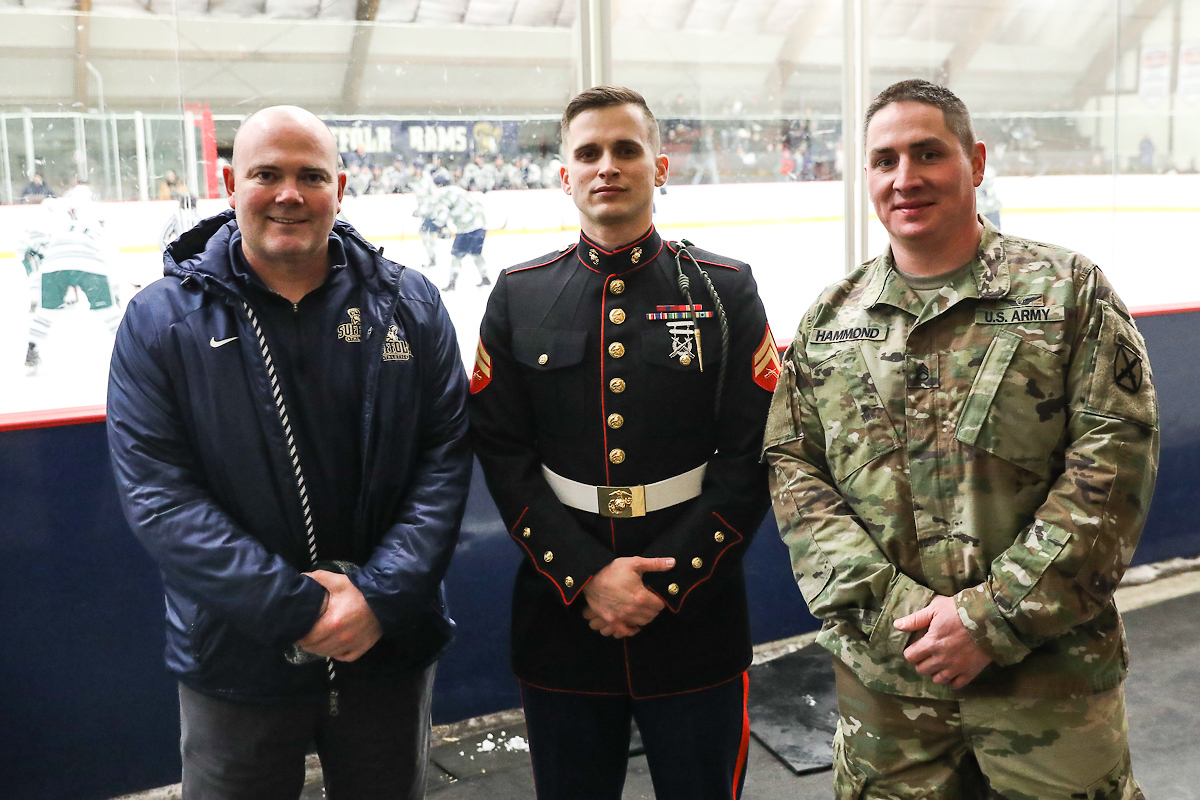 Suffolk athletic director standing with military members.