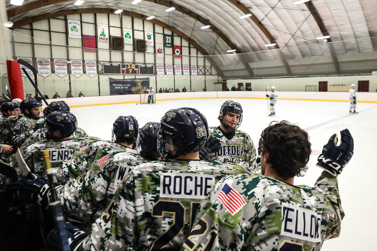 Suffolk player skates by teammates who are wearing camo jerseys.