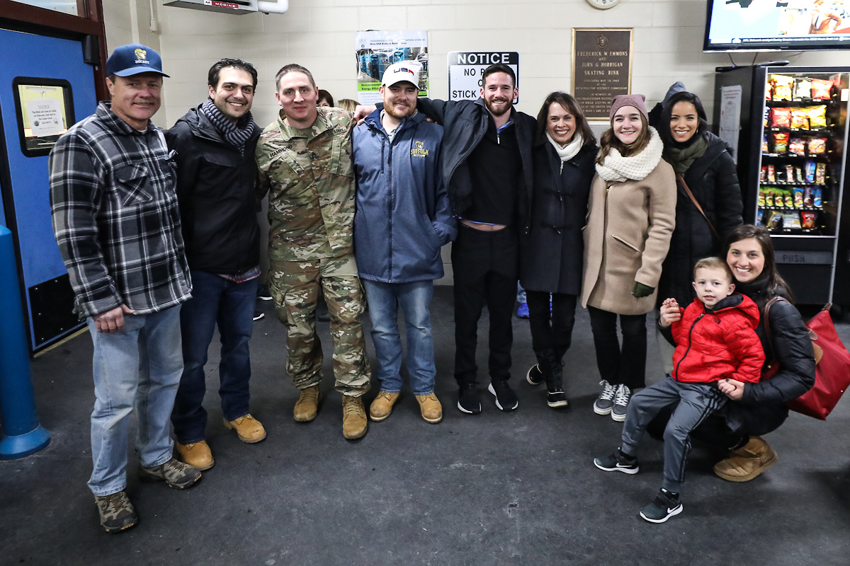 Fans, players, and veterans stand outside of the rink. 