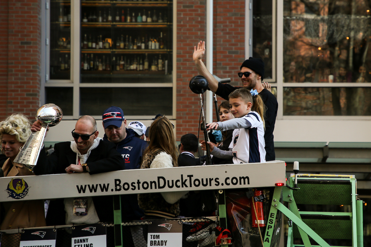 Tom Brady pointing to the crowd at the Patriots Parade in front of Suffolk University.
