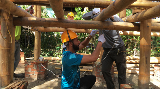 Two Suffolk students connecting electric wires in the frame of a house during a Habitat for Humanity trip in Asia.