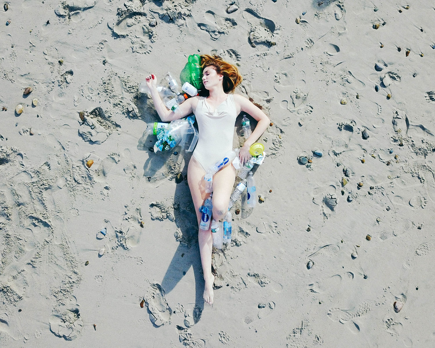 Student Laying on beach covered in trash